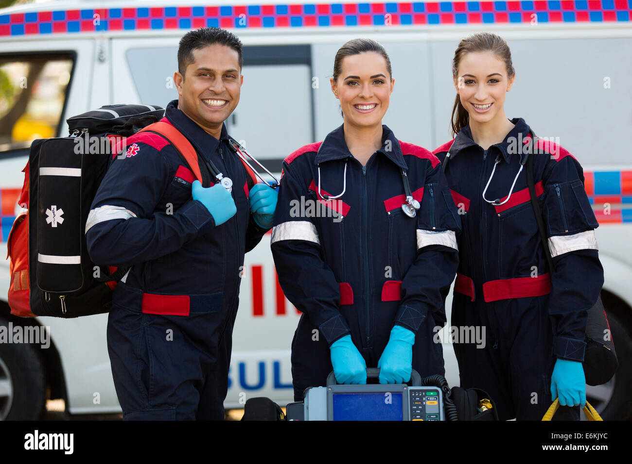 Felice paramedici trasportano attrezzature portatili di fronte ambulanza Foto Stock