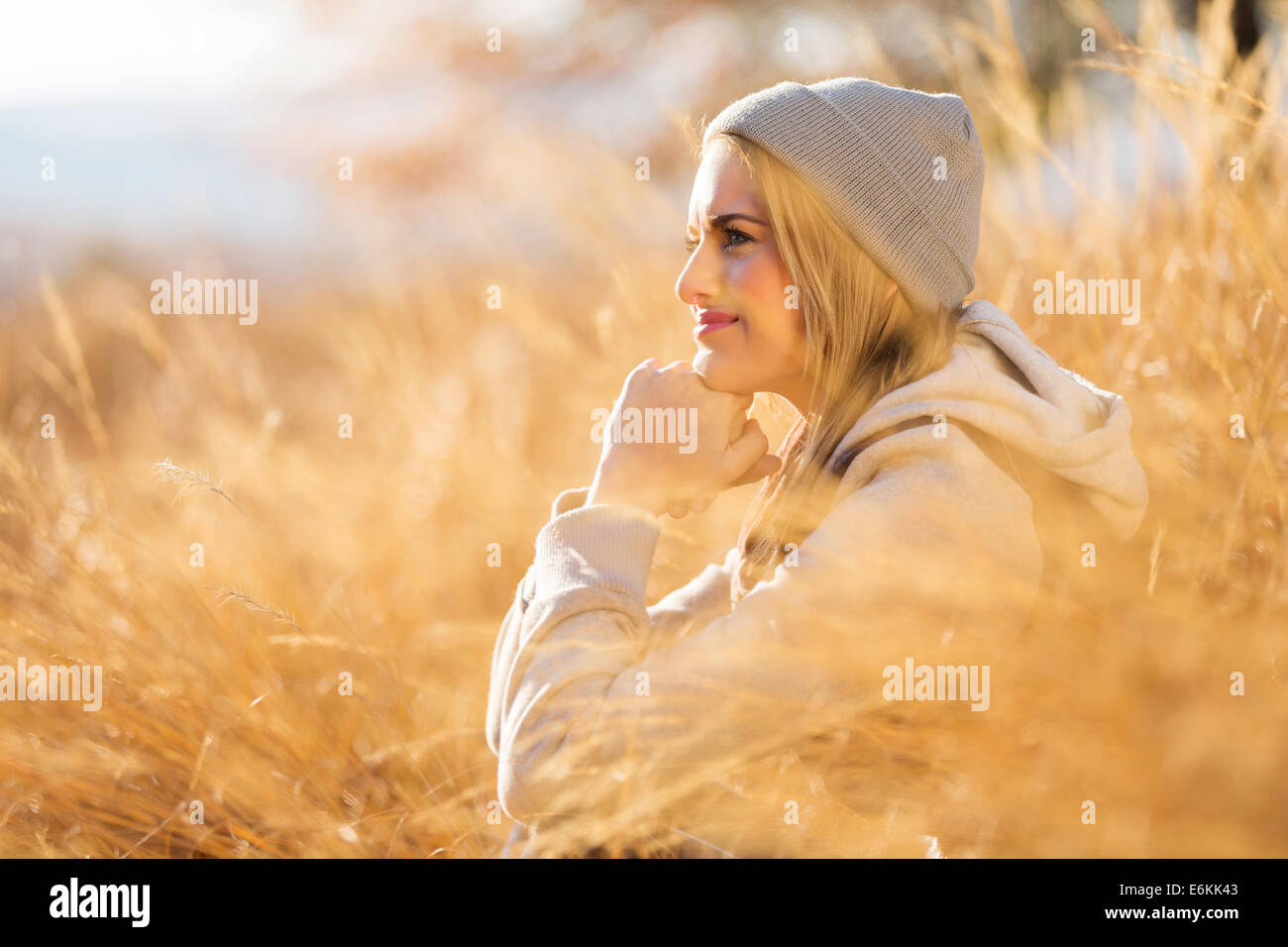 Premurosa donna seduta in erba alta in autunno Foto Stock