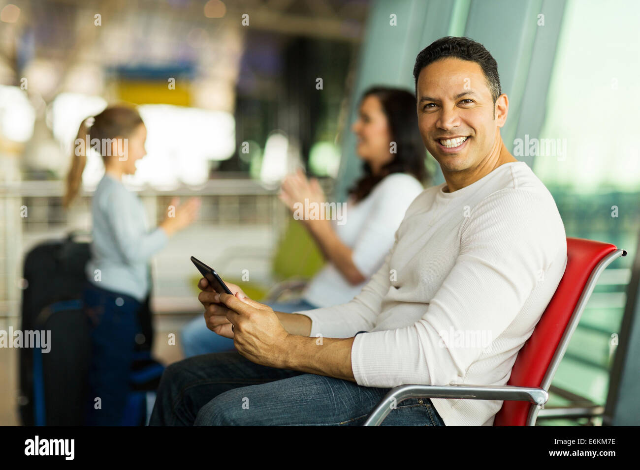 Bello padre utilizzando computer tablet all'aeroporto mentre aspetta per il volo con la famiglia Foto Stock