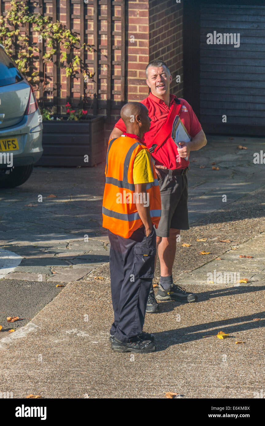 Un furgone corriere driver a chiacchierare con un postino felice facendo il suo post round di Royal Mail Pantaloncino estivo uniforme. Banstead, Surrey, Inghilterra, Regno Unito. Foto Stock
