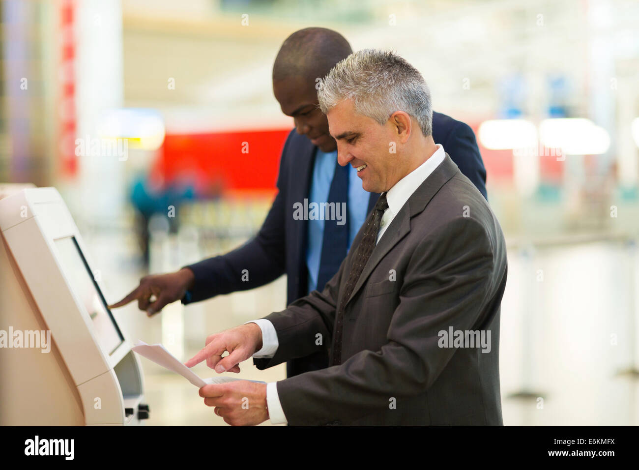Due professionisti sempre in viaggio utilizzando self help controllare in macchina all'aeroporto Foto Stock Due professionisti sempre in viaggio utilizzando self help controllare in macchina all'aeroporto Foto Stock