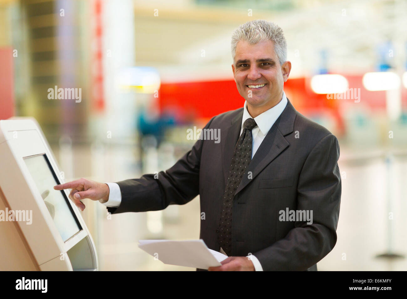 Happy businessman mature utilizzando self help controllare in macchina all'aeroporto Foto Stock