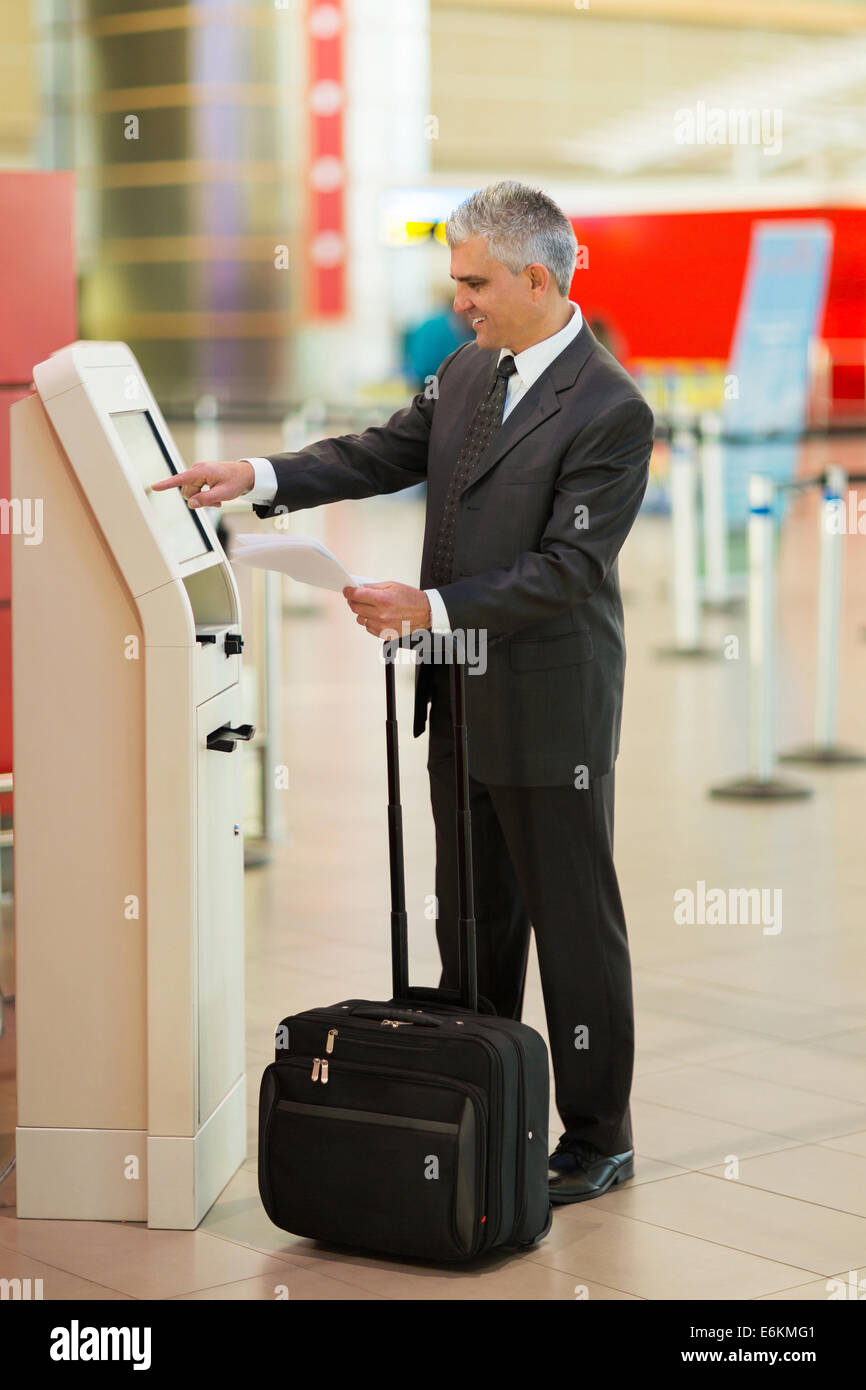 Persone di mezza età imprenditore utilizzando self help controllare in macchina all'aeroporto Foto Stock Persone di mezza età imprenditore utilizzando self help controllare in macchina all'aeroporto Foto Stock
