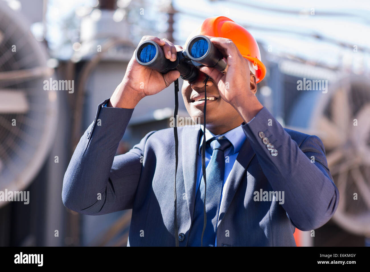Africa tecnico elettricista con un binocolo guardando alla sottostazione elettrica Foto Stock
