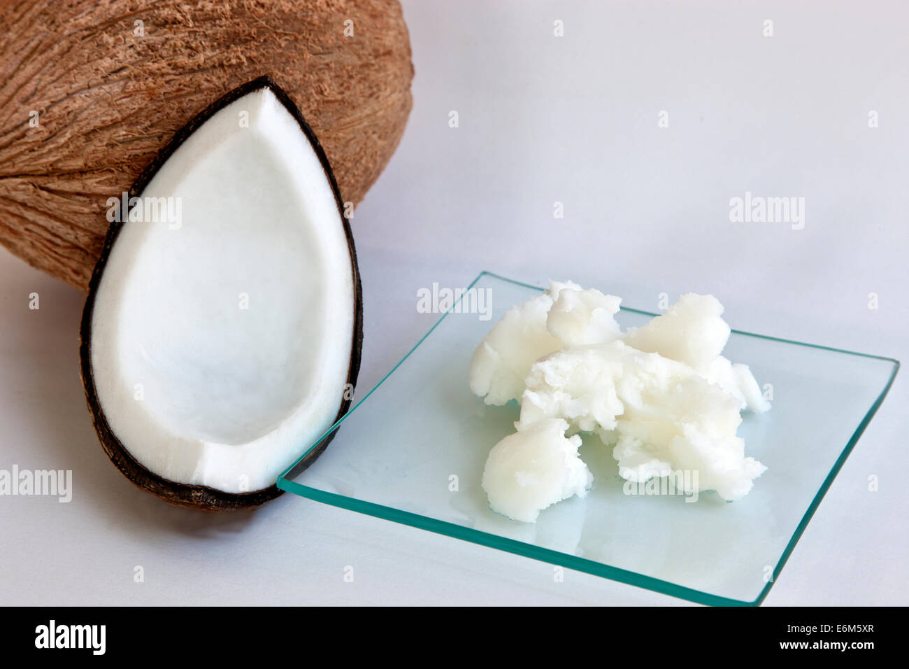 Olio di noce di cocco 'semi solidi" sul piatto di vetro, squartati & tutta la noce di cocco. Foto Stock