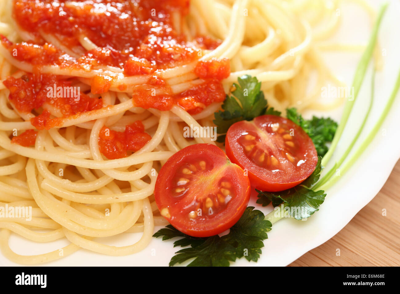 Spaghetti su una piastra con salsa di pomodoro e i pomodori con il prezzemolo verde. Primo piano. Foto Stock