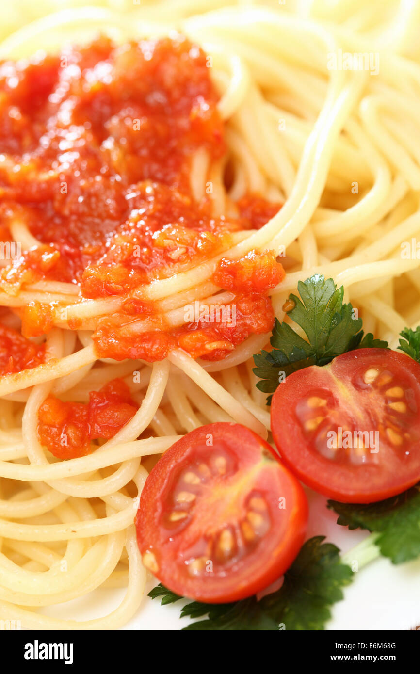 Spaghetti su una piastra con salsa di pomodoro e i pomodori con il prezzemolo verde . Primo piano. Foto Stock