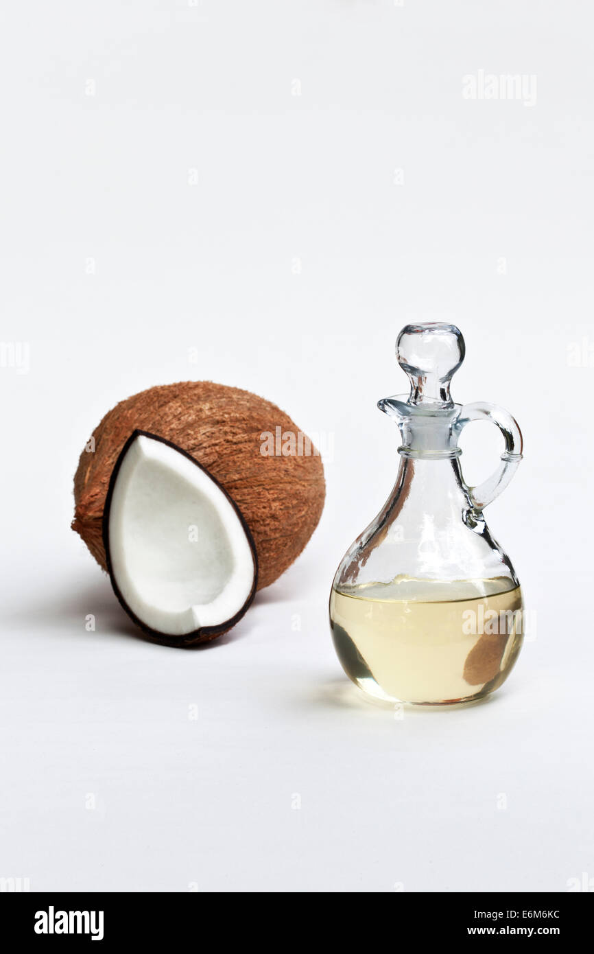 Olio di noce di cocco nella caraffa di vetro, squartati & tutta la noce di cocco. Foto Stock