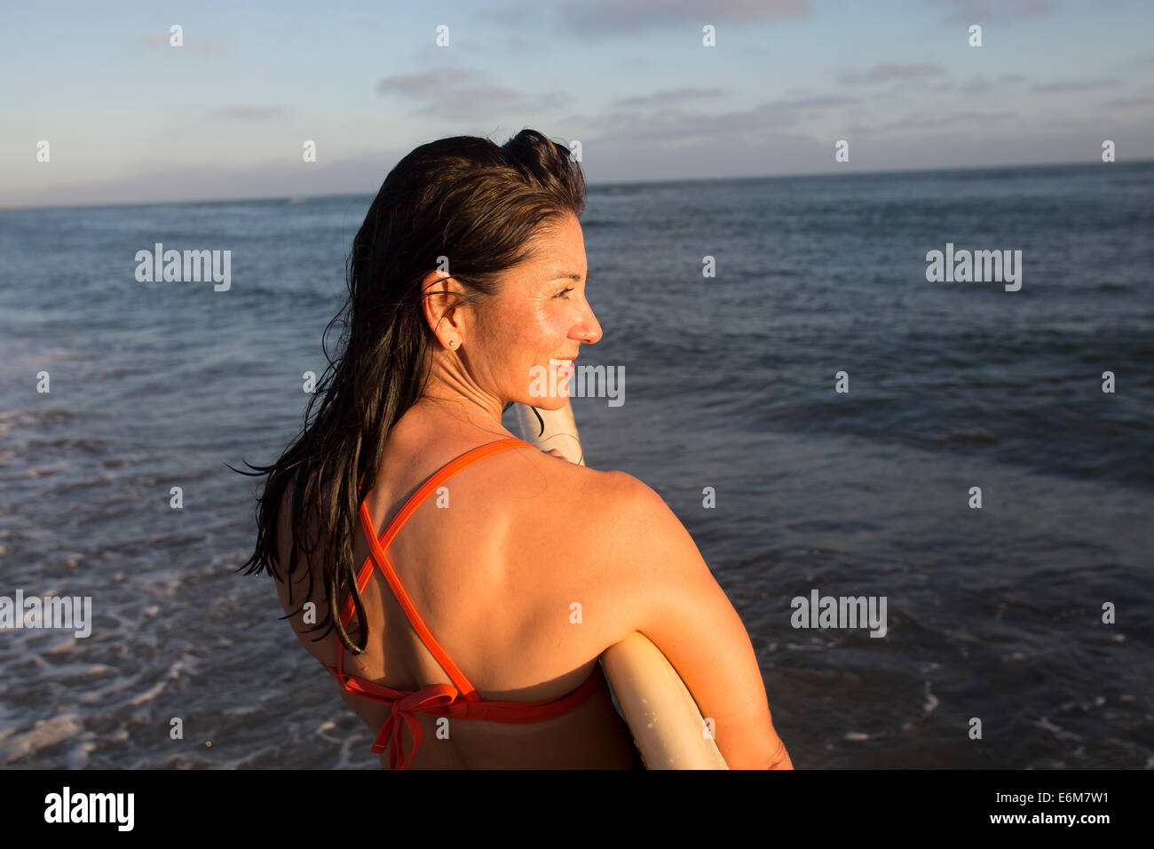 Donna che mantiene le tavole da surf e permanente al beach Foto Stock