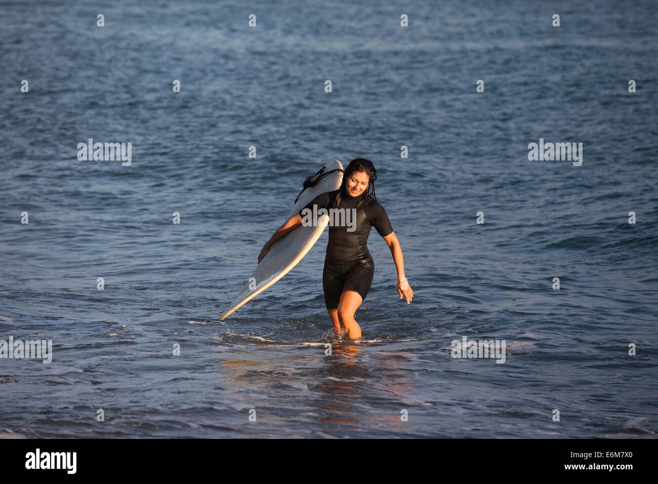 Donna che mantiene le tavole da surf e ottenere al di fuori dell'acqua Foto Stock