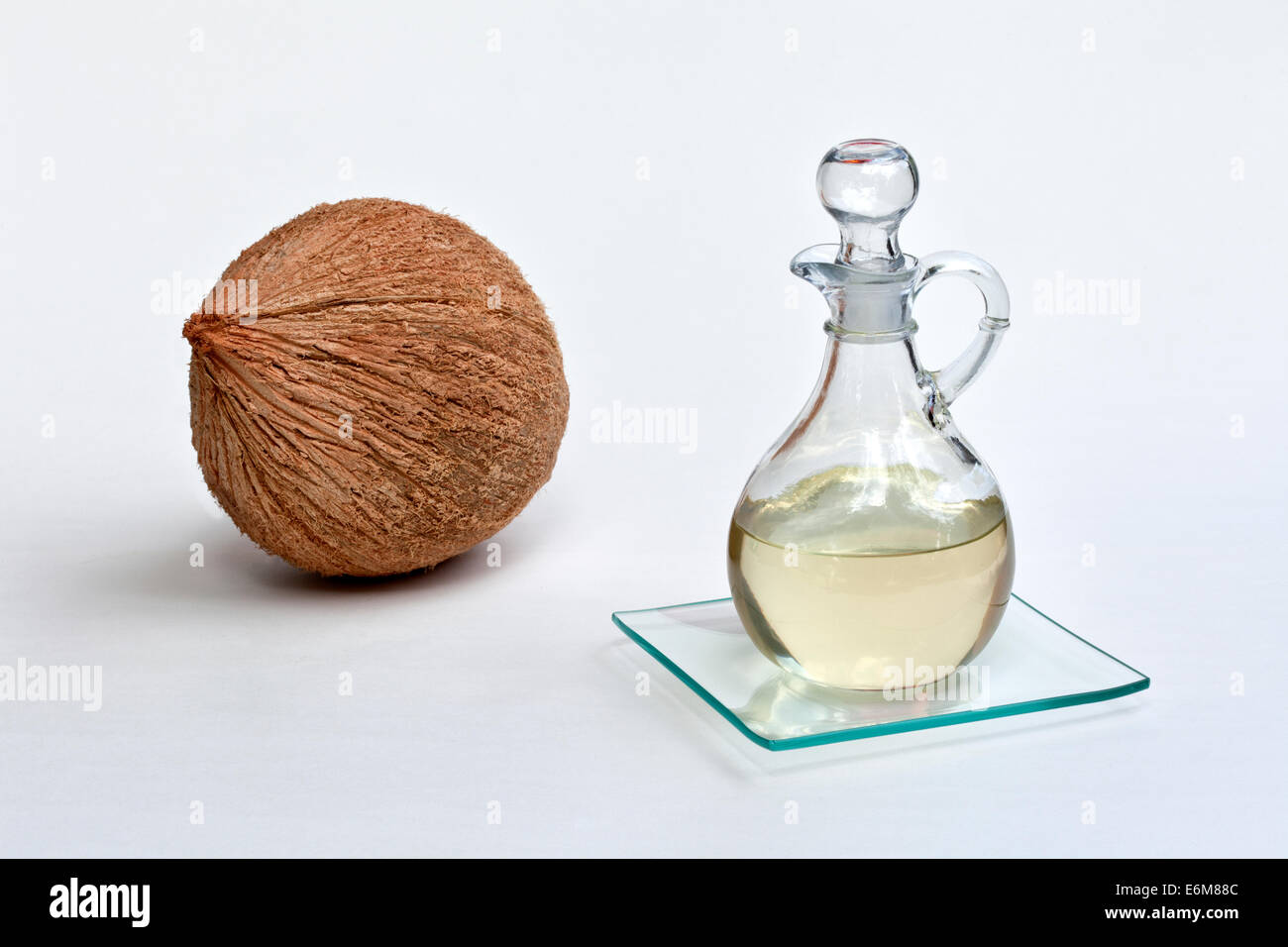 Olio di noce di cocco nella caraffa di vetro, tutta la noce di cocco. Foto Stock