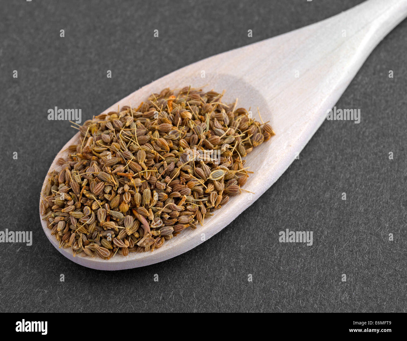 Molto vicino in vista di un cucchiaio di legno riempita con i semi di anice su uno sfondo scuro. Foto Stock