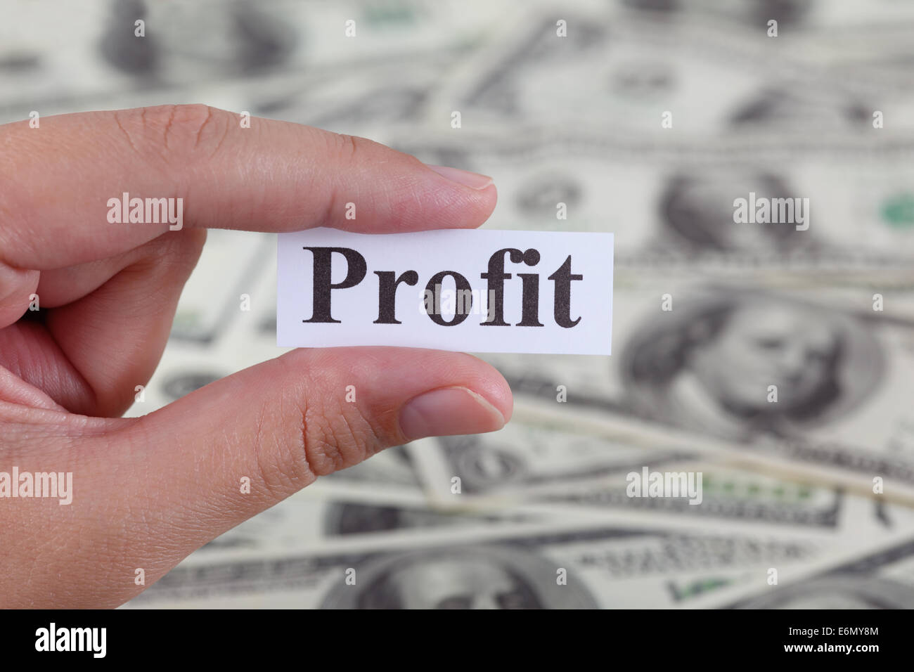 Donna di mano che tiene un pezzo di carta con la parola 'profitto' contro il dollaro dello sfondo. Close-up. Foto Stock