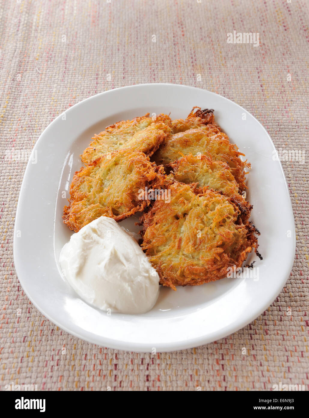 Frittelle di patate con panna acida sulla piastra bianca Foto Stock