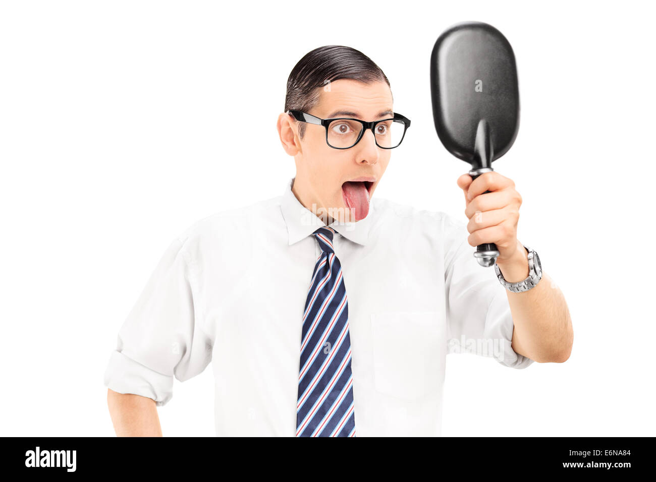 Uomo che guarda in uno specchio e bloccato la sua lingua fuori isolati su sfondo bianco Foto Stock