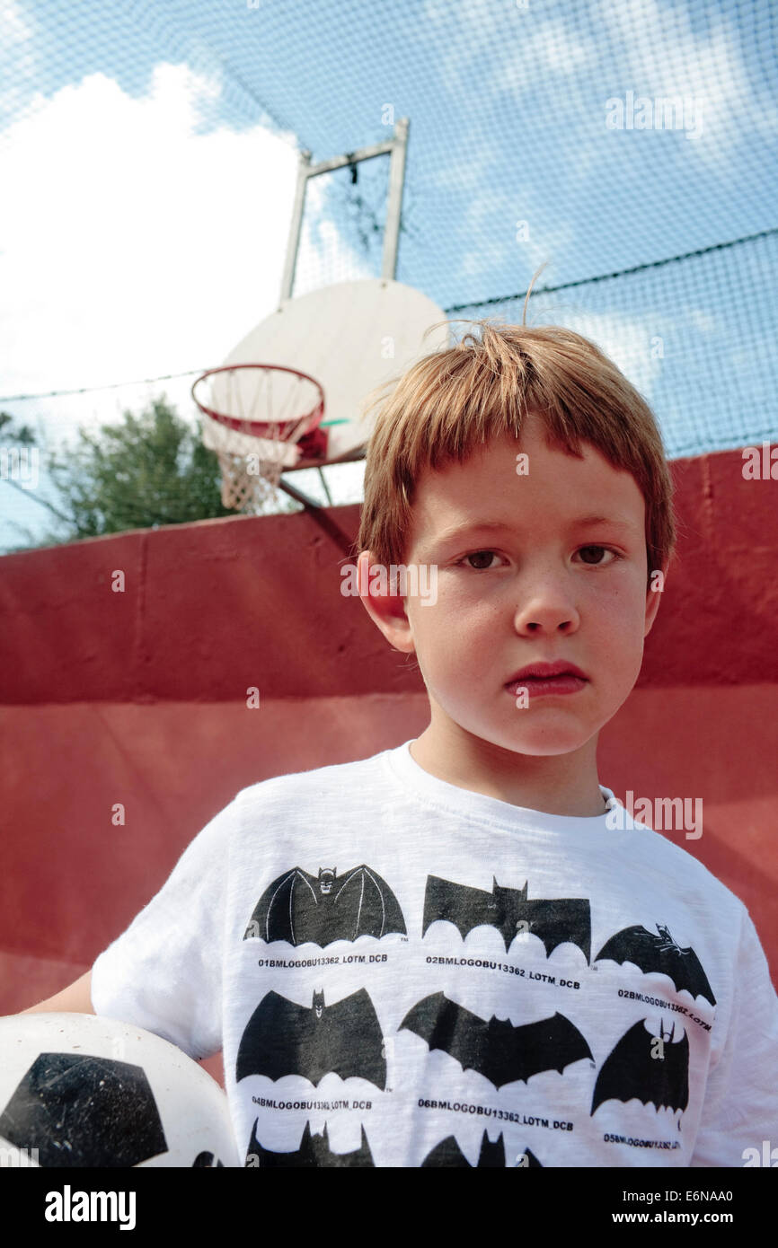 Ritratto di un periodo di cinque anni a old boy tenendo un calcio in un multi-purpose giudice sportivo Foto Stock