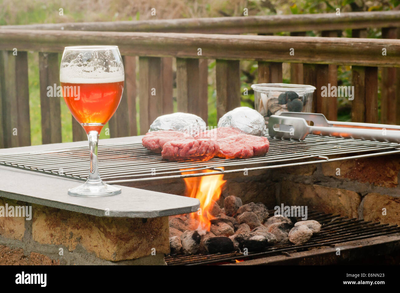 Gli hamburger su una fiammante Barbecue Grill con una classe di birra artigianale Foto Stock