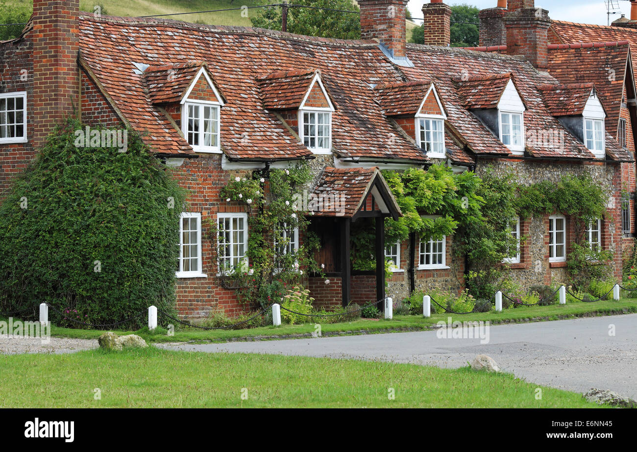 Tradizionale villaggio Inglese in mattoni e pietra focaia Cottage con piante rampicanti sulla parete Foto Stock