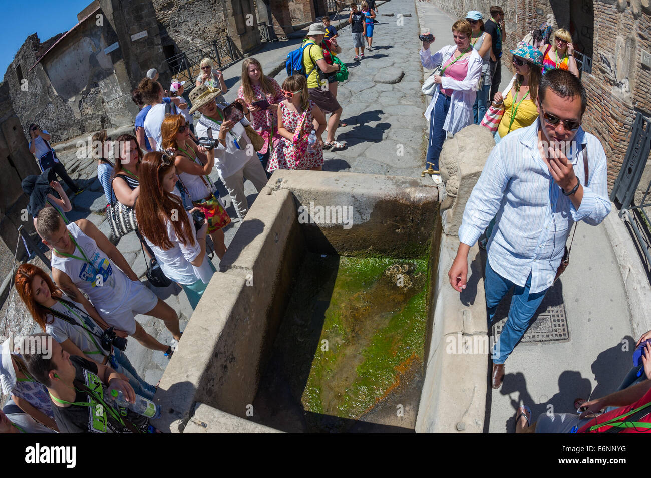 Guida turistica di parlare ai visitatori attorno ad un'acqua potabile in bene le rovine di una città romana di Pompei in Italia. Foto Stock