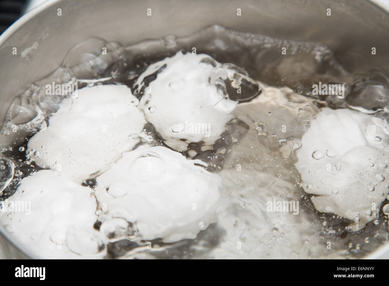 Bollire le uova in una pentola di acqua calda Foto Stock