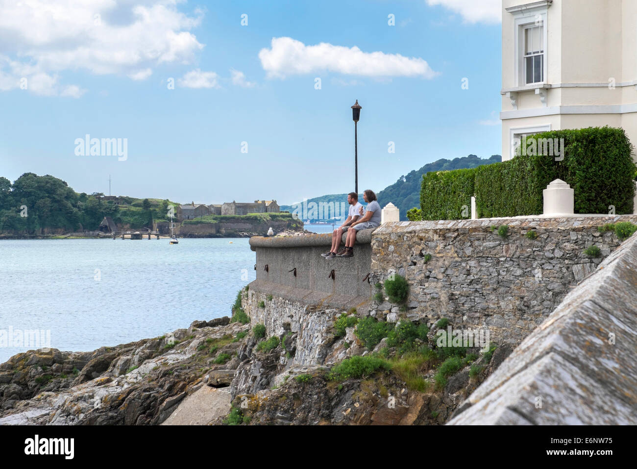 Due persone sedute su una parete guardando il mare a Plymouth Hoe, Plymouth, Devon, Inghilterra, Regno Unito Foto Stock