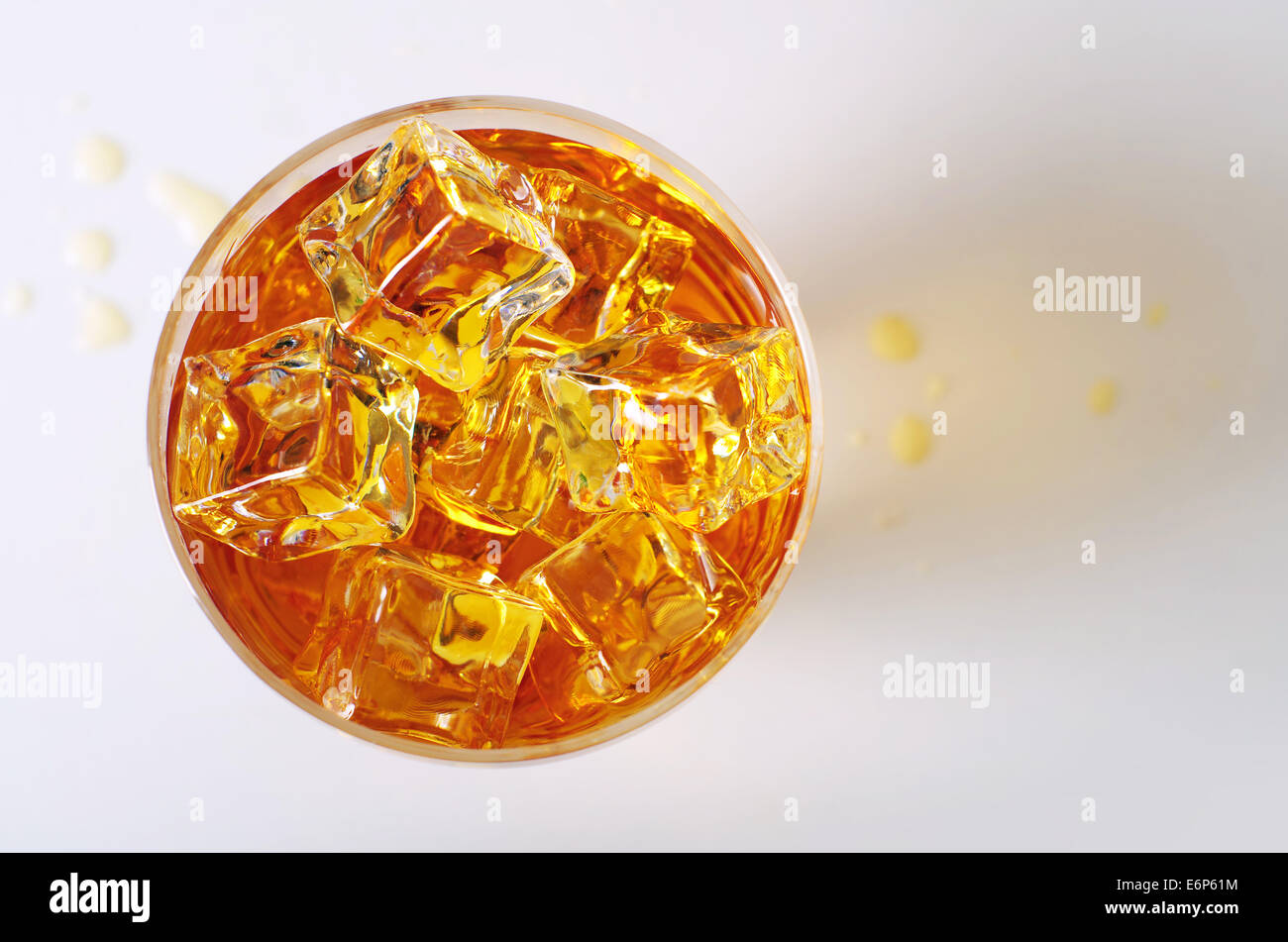 Vista dall'alto sulla bevanda alcolica in un bicchiere con cubetti di ghiaccio e la fuoriuscita di gocce sul tavolo Foto Stock