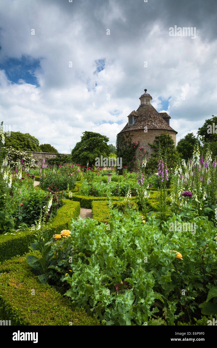 La casella-parterre coperto con fiori estivi e c.1685 colombaia in il giardino murato di Rousham House, Oxfordshire, Inghilterra Foto Stock