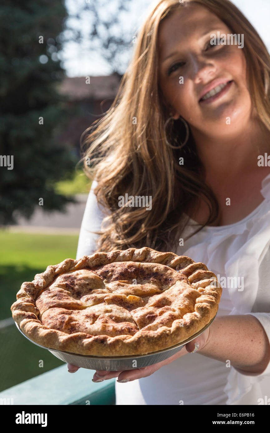 Bella giovane donna che mostra in casa torta di mele, STATI UNITI D'AMERICA Foto Stock