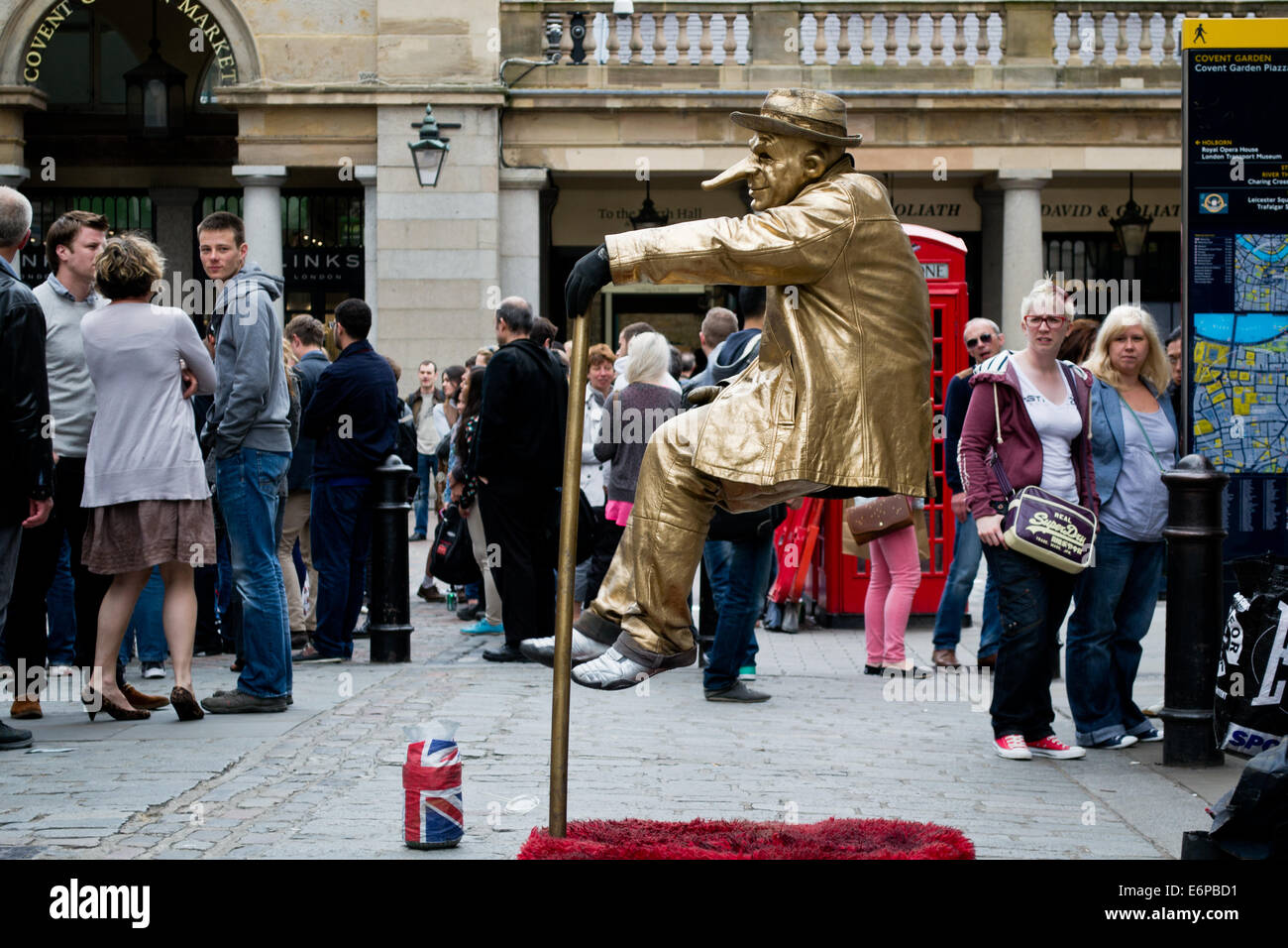 Un oro adatti street performer di Covent Garden, Londra, entusiasma i visitatori con l'apparente capacità di sedersi in sospensione nell'aria Foto Stock