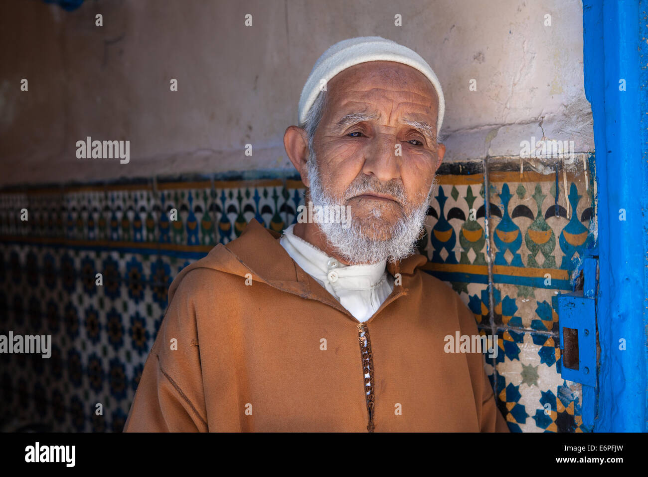 Il vecchio uomo musulmano, indossando un tradizionale djellaba, in piedi in una porta nella vecchia medina di Essaouira, Marocco. Modello rilasciato. Foto Stock