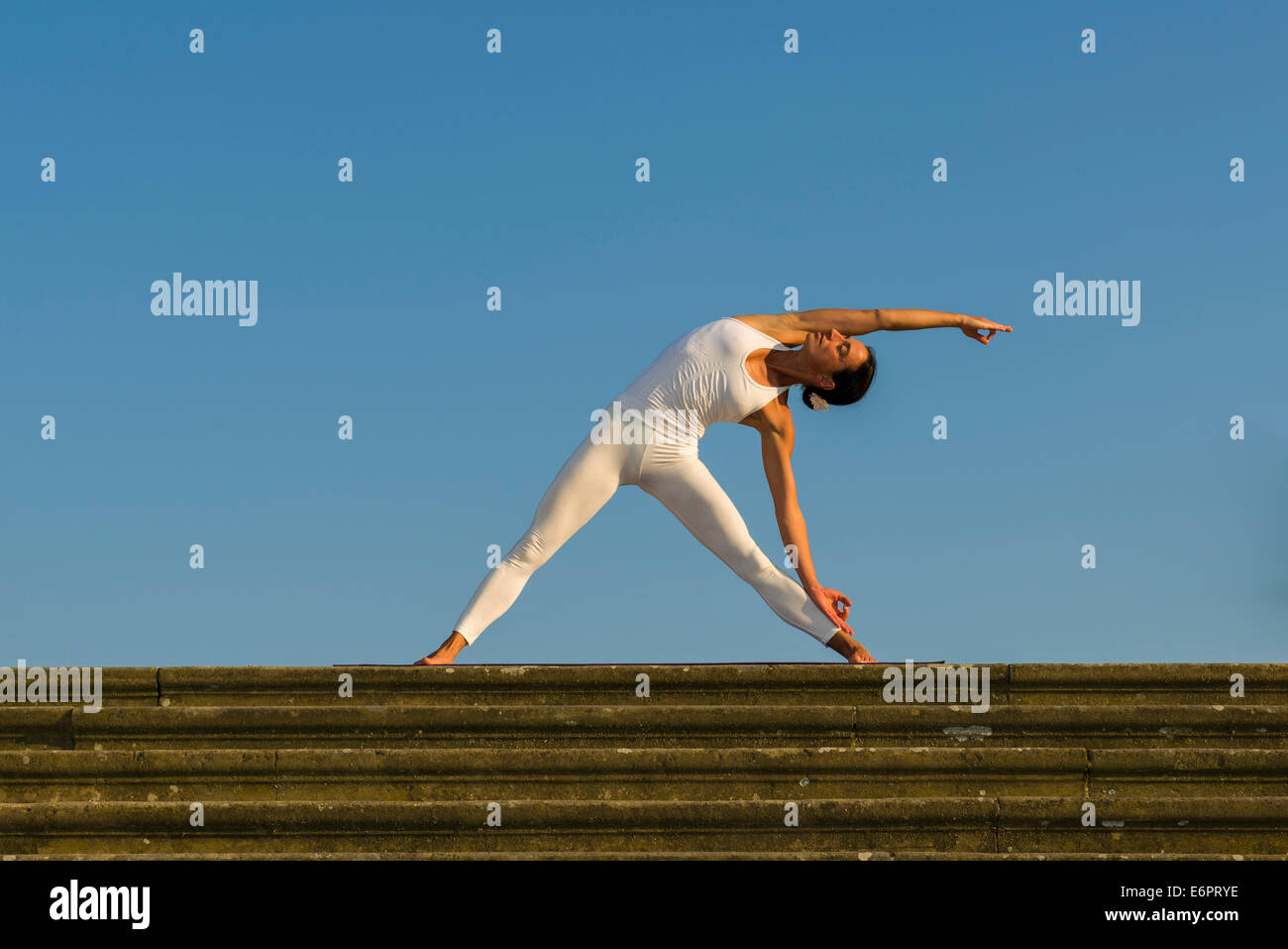 Giovane donna pratica di Hatha yoga, all'aperto, che mostra la posa Trikonasana, Triangolo Foto Stock