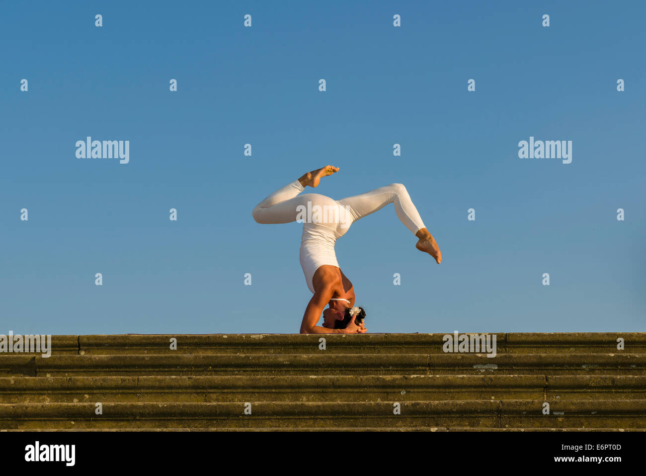 Giovane donna pratica di Hatha yoga, all'aperto, che mostra la posa Sirshasana, testa stand Foto Stock