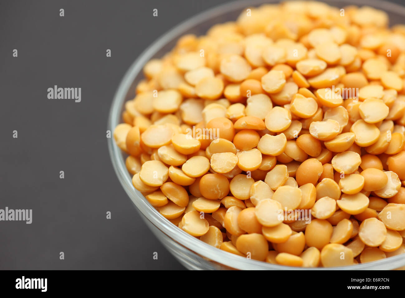 Split piselli gialli in una ciotola di vetro su sfondo nero Foto Stock