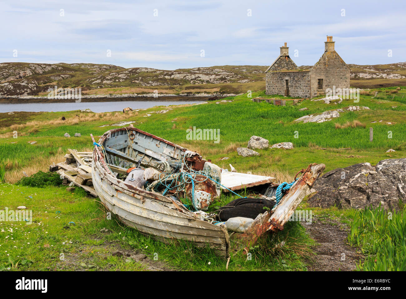 La scena delle Ebridi con la vecchia barca da pesca e abbandonata croft cottage nel paesaggio scozzese di Loch Sgioport, Sud Uist, Ebridi Esterne, Scotland, Regno Unito Foto Stock