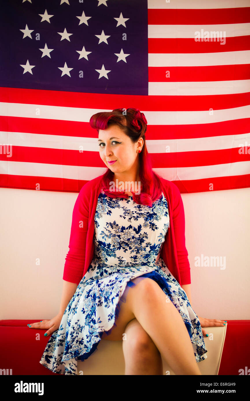 Una donna che indossa 50's stile di abbigliamento retrò seduto davanti a  una bandiera degli Stati Uniti a stelle e strisce banner Foto stock - Alamy
