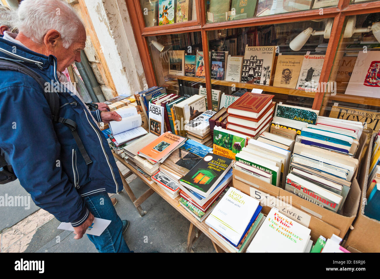 Un uomo francese di sfogliare i libri sul display in strada, al di fuori di una libreria francese Foto Stock
