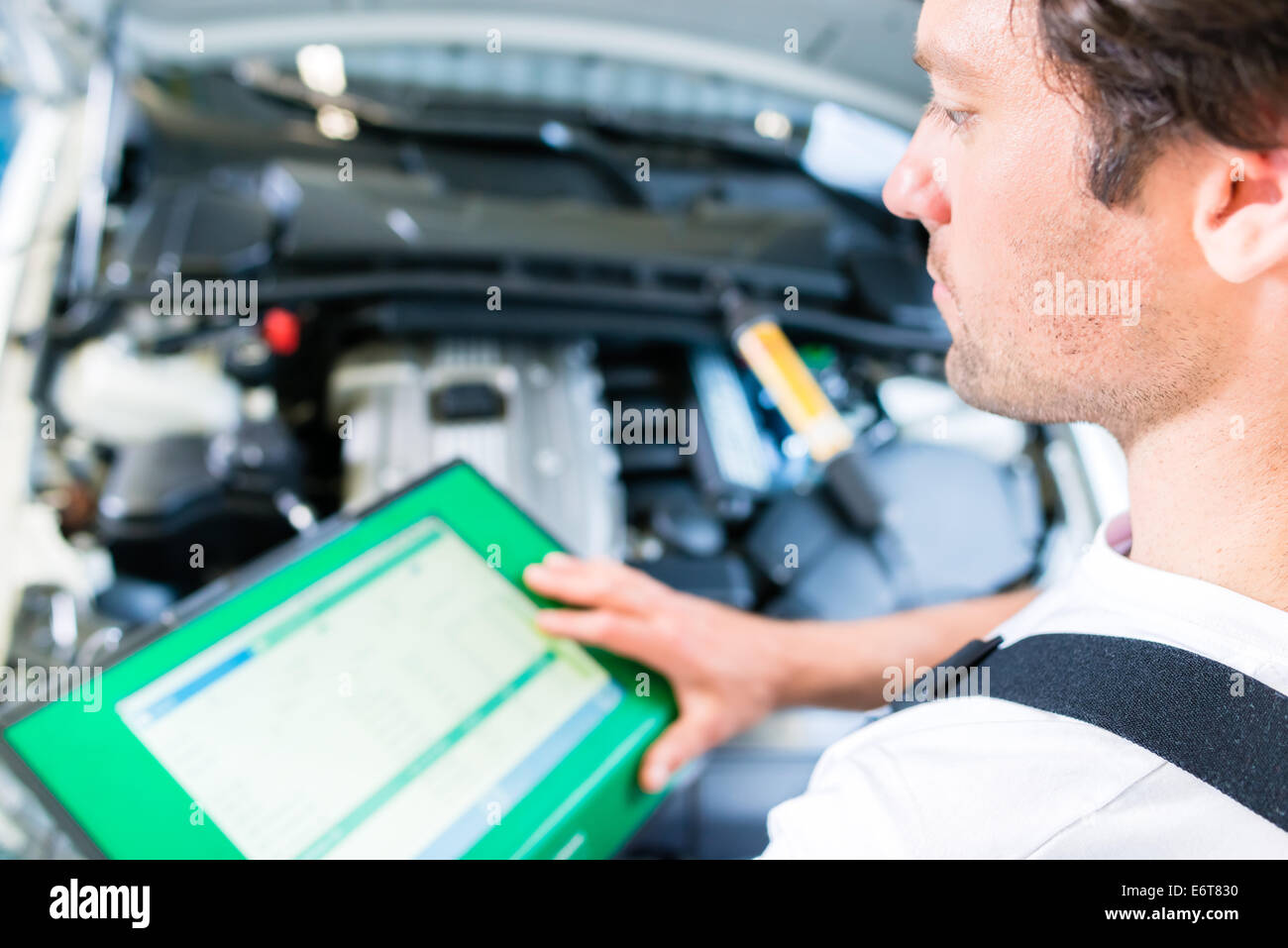 Meccanico con un apparecchio di diagnosi in officina per auto Foto Stock