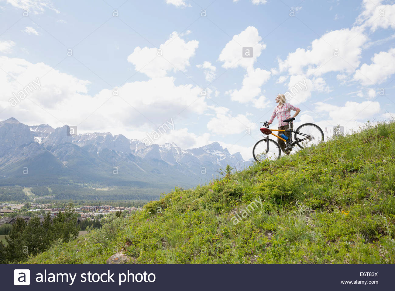 Donna in piedi con mountain bike su pendio Foto Stock