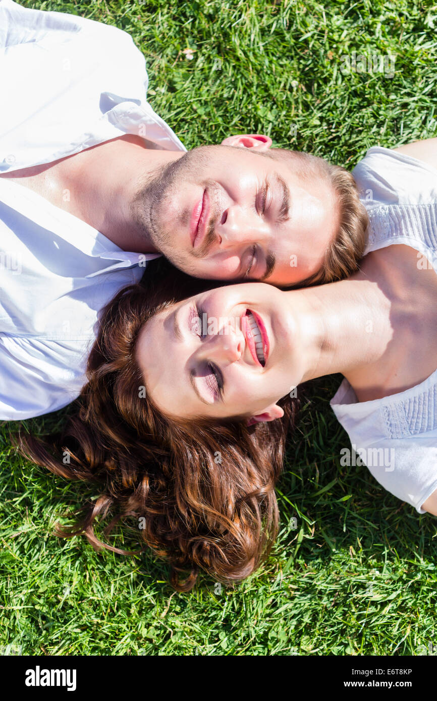 Gli amici la posa di fianco a fianco sul prato del Parco godendo di Sun Foto Stock