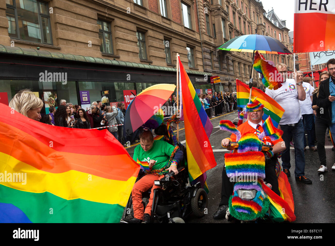 Copenhagen, Danimarca. Il 30 agosto, 2014. Copenhagen Pride Week 2014 conclude è 4 giorni di evento con un 3 ore di lunga e spettacolare Pride Parade attraverso la parte interna della città di Copenhagen. Più di 20.000 persone hanno partecipato alla sfilata che è stata accolta da alcune centinaia di migliaia di spettatori lungo il percorso, gli organizzatori di stime. Sulla foto 2 (foto, metà) 2 portatori di handicap in carrozzina con l'orgoglio bandiera prende parte alla parata. Credito: OJPHOTOS/Alamy Live News Foto Stock