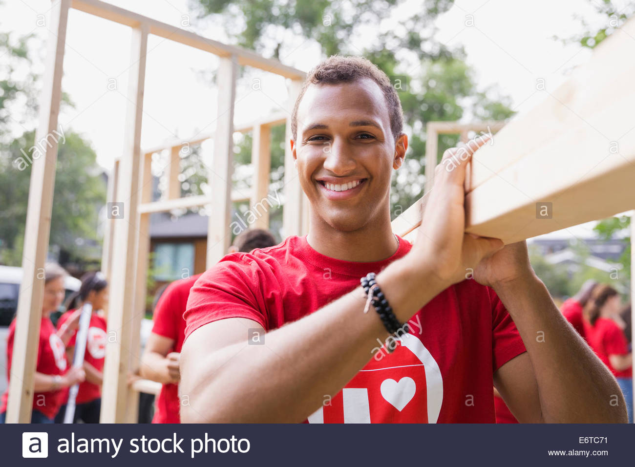 Ritratto di volontario sorridente trasportare il legno Foto Stock
