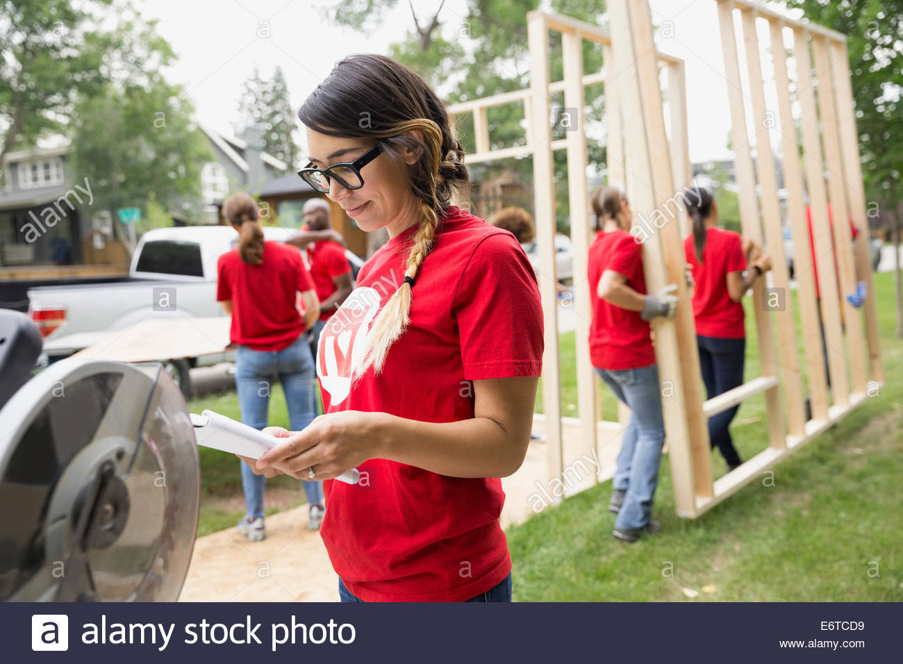Volontario con blueprint vicino al telaio di costruzione Foto Stock