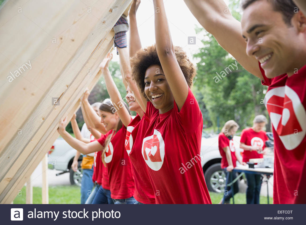 Ritratto di volontari sorridente sollevamento telaio di costruzione Foto Stock