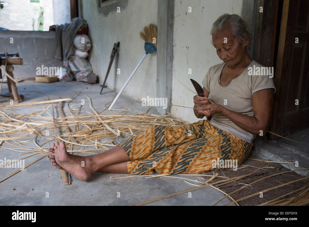 Yogyakarta, Java, Indonesia. Vecchia donna Preparazione Palm Frond strisce per Basket-Making. Foto Stock