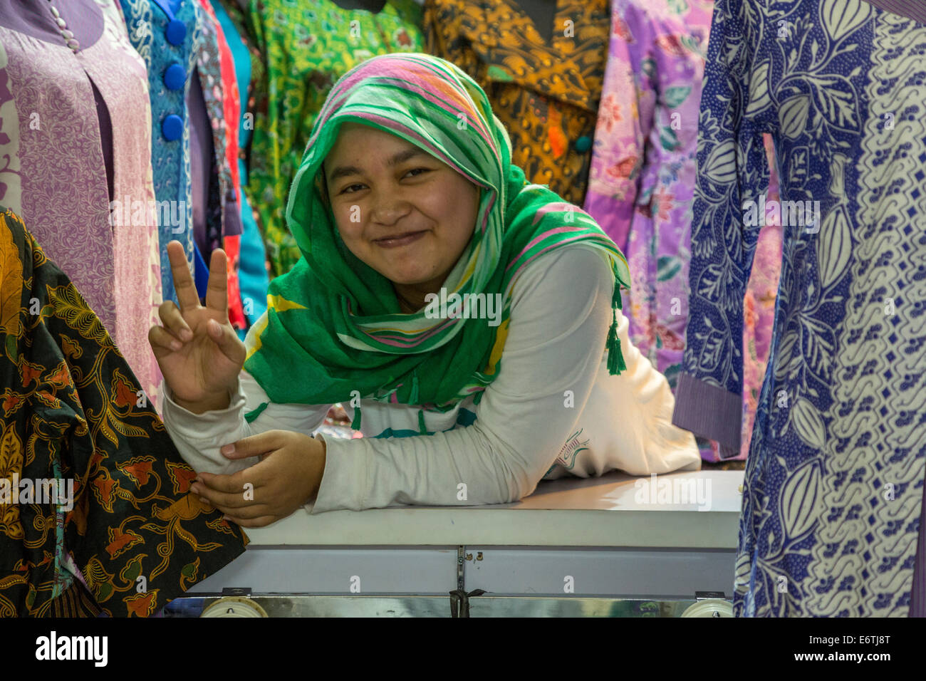 Yogyakarta, Java, Indonesia. Giovane donna commesso in un negozio di abbigliamento, Beringharjo mercato. Foto Stock