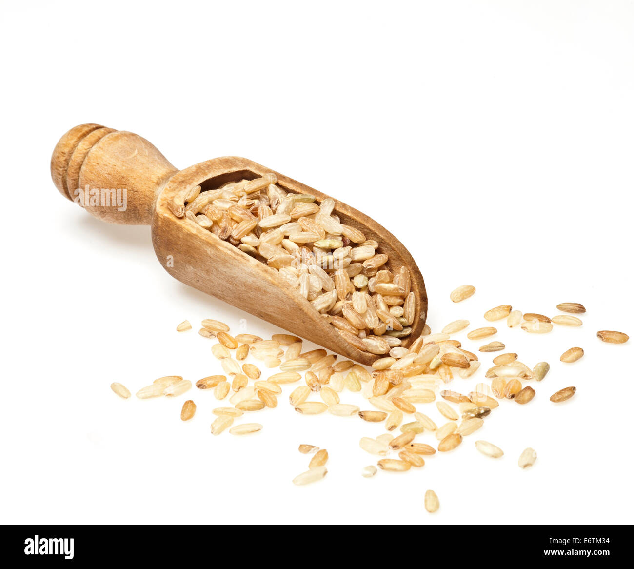 Cucchiaio di legno con il riso bruno sparsi su sfondo bianco. Foto Stock