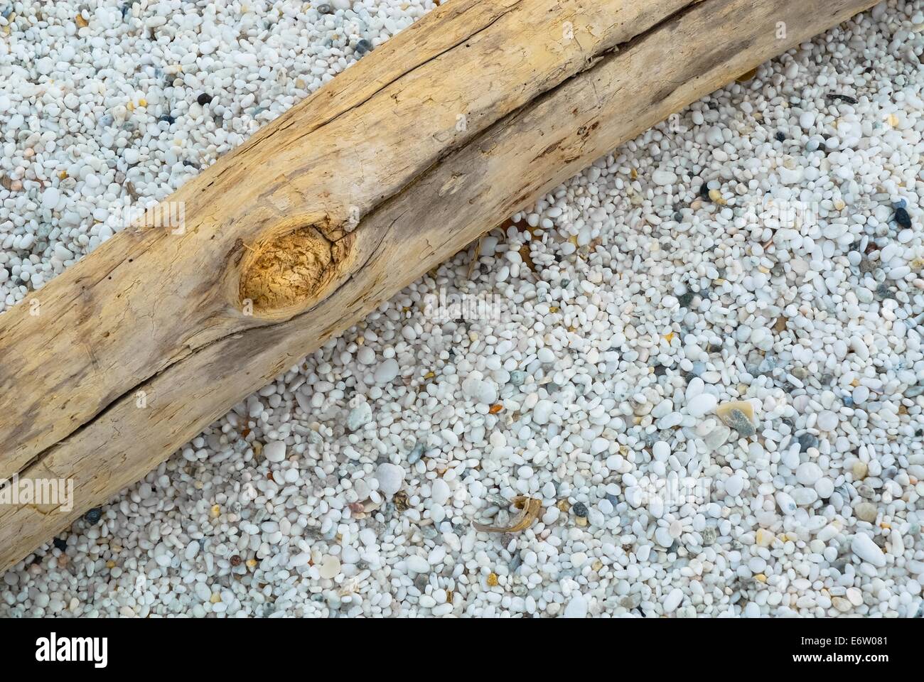 Un pezzo di legno in spiaggia e pebbels bianco Foto Stock