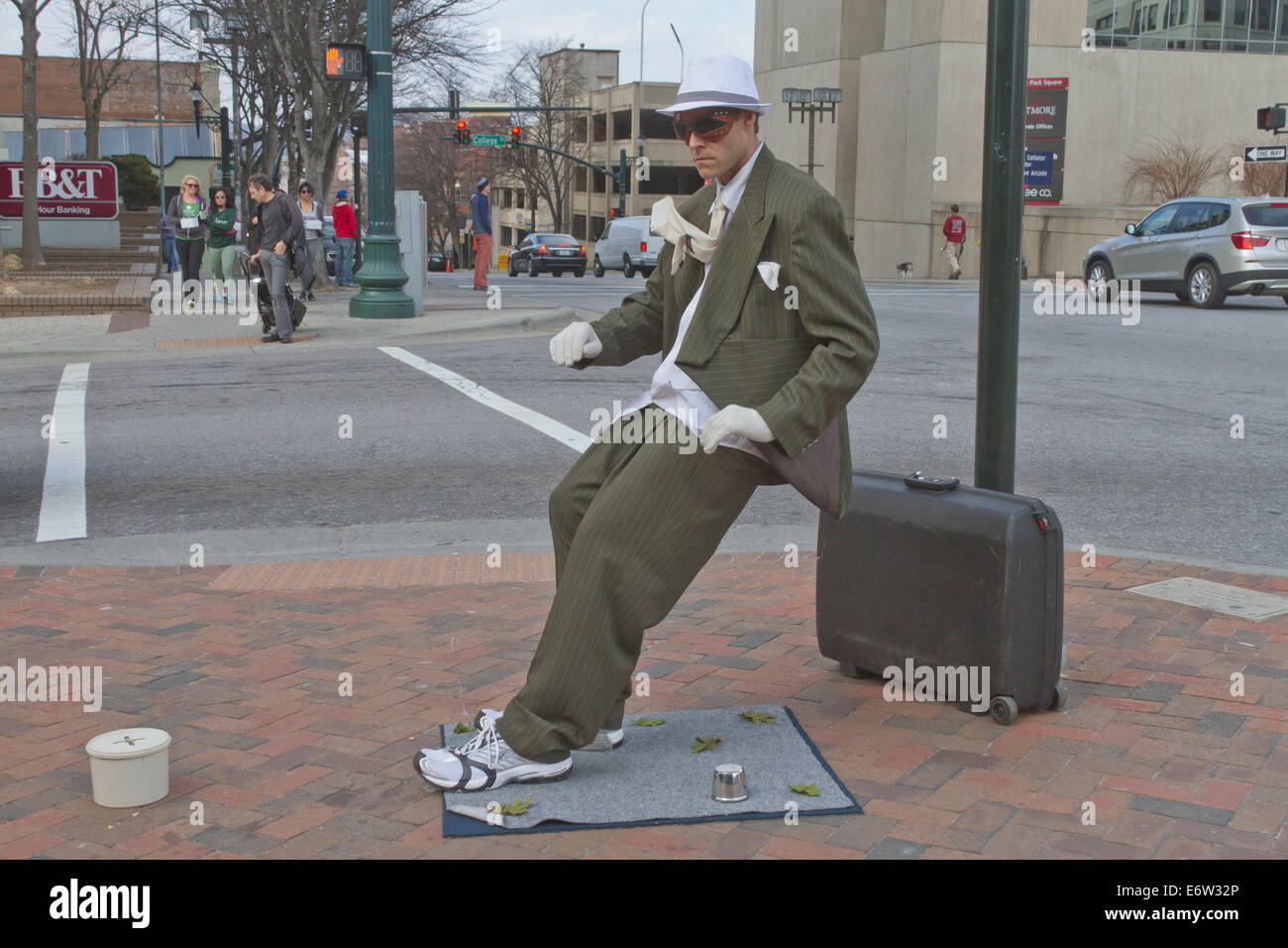 Maschio statua vivente street busker esegue per consigli indossa una tuta ed inclinati ad un angolo impossibile nel centro di Asheville, NC Foto Stock