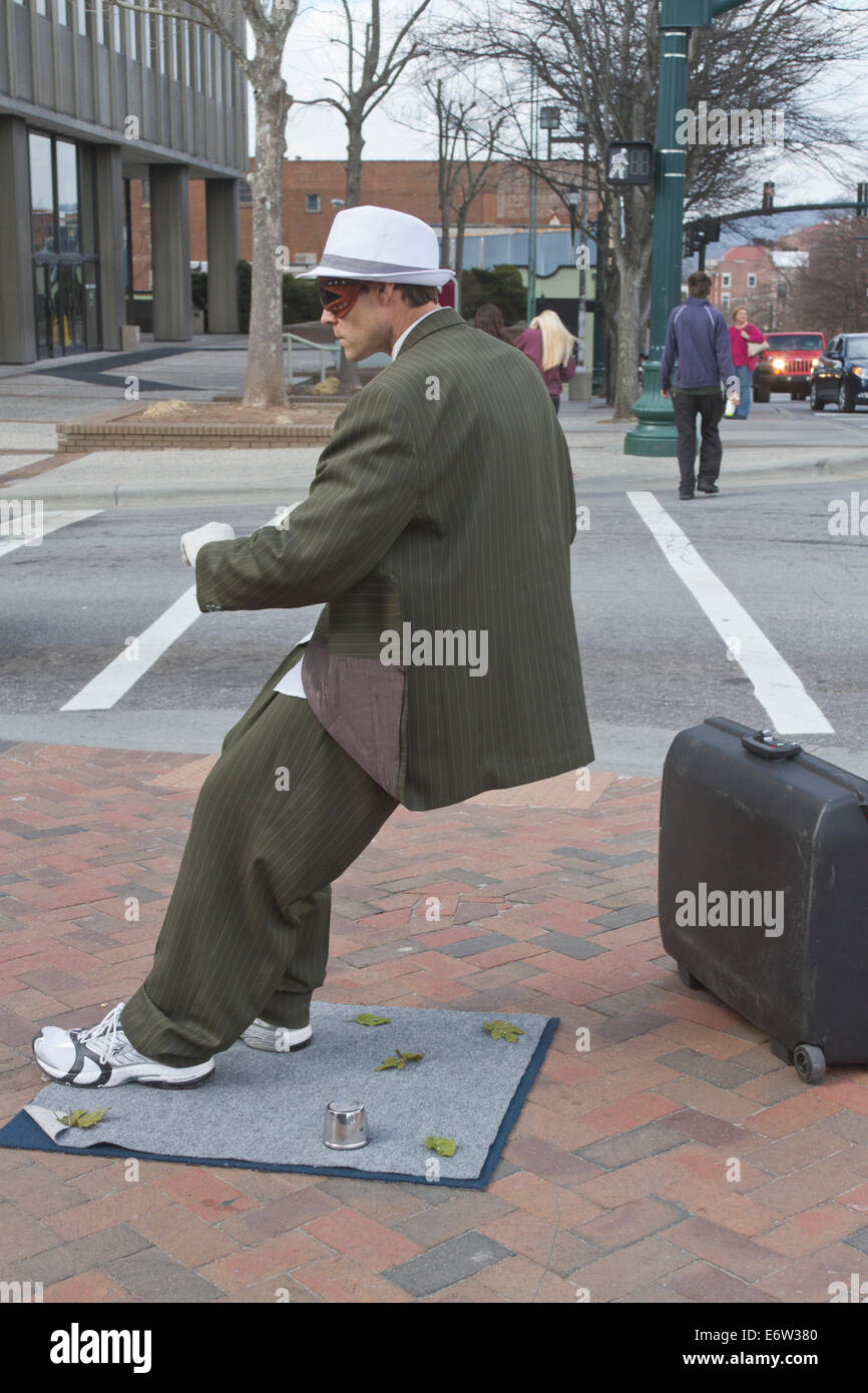 Maschio statua vivente street busker esegue per consigli indossa una tuta ed inclinati ad un angolo impossibile nel centro di Asheville, NC Foto Stock