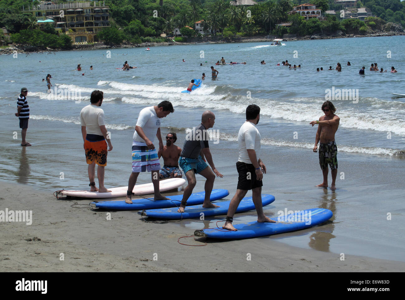 Gli uomini in piedi sulla tavola da surf in spiaggia durante una lezione di surf in Sayulita, Messico. Foto Stock